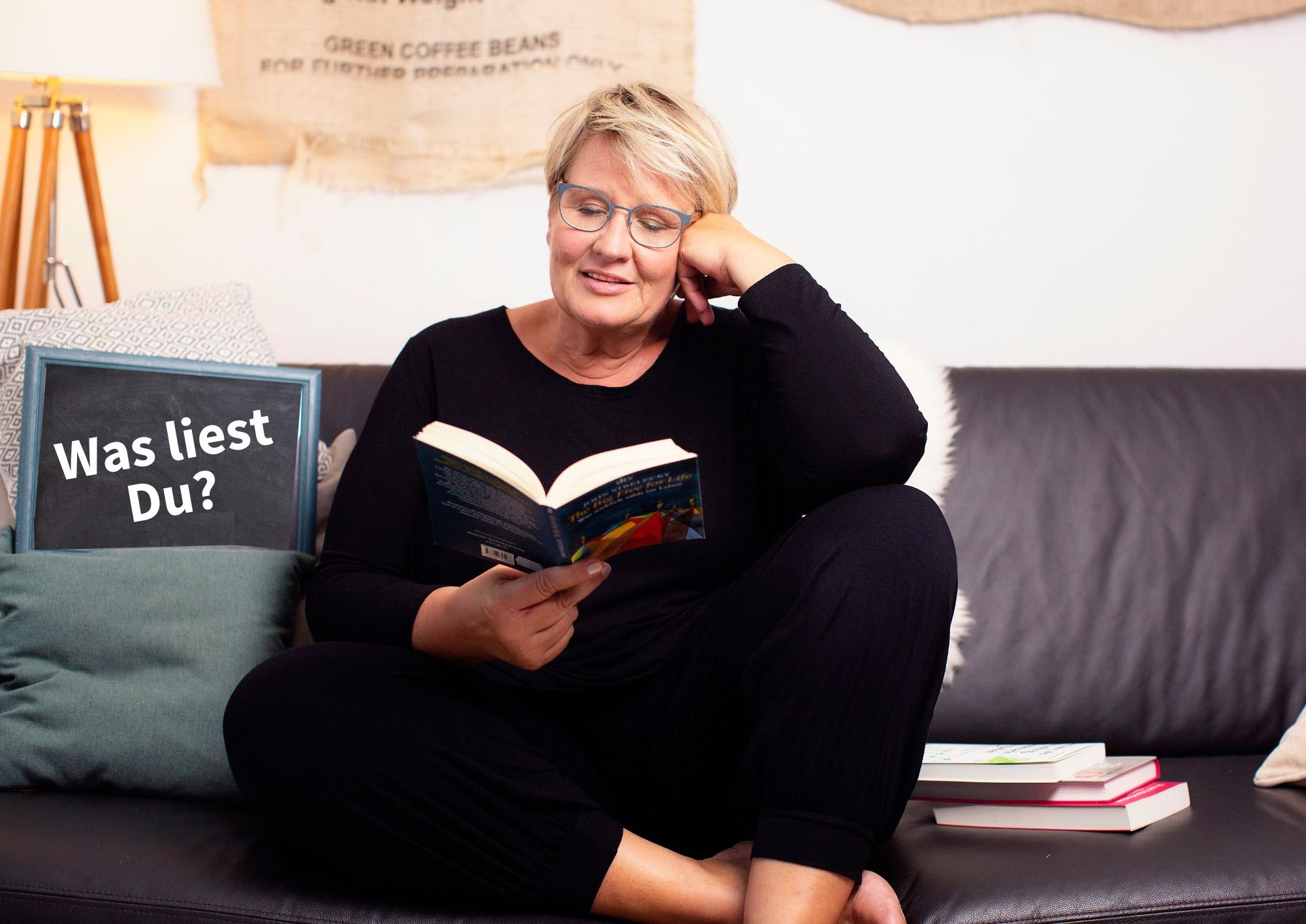 Tanja Köhler sitzt auf einem Sofa und liest ein Buch.